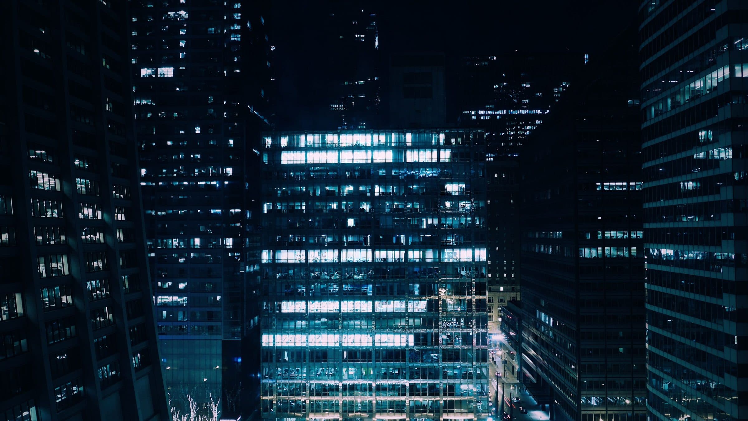 Office towers at night, one facade fully lit among dark neighbours