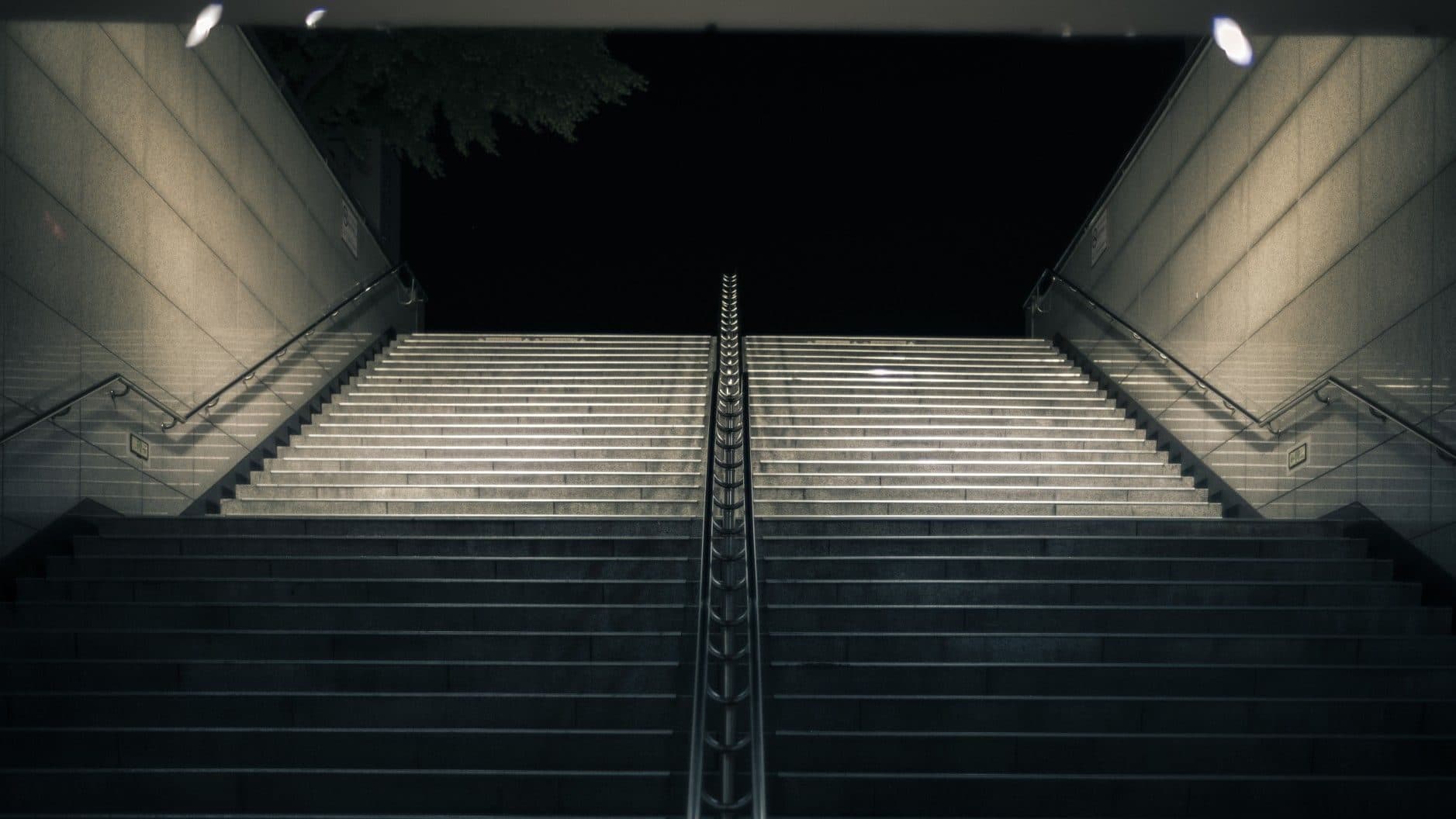 Wide concrete staircase descending into a dark entrance