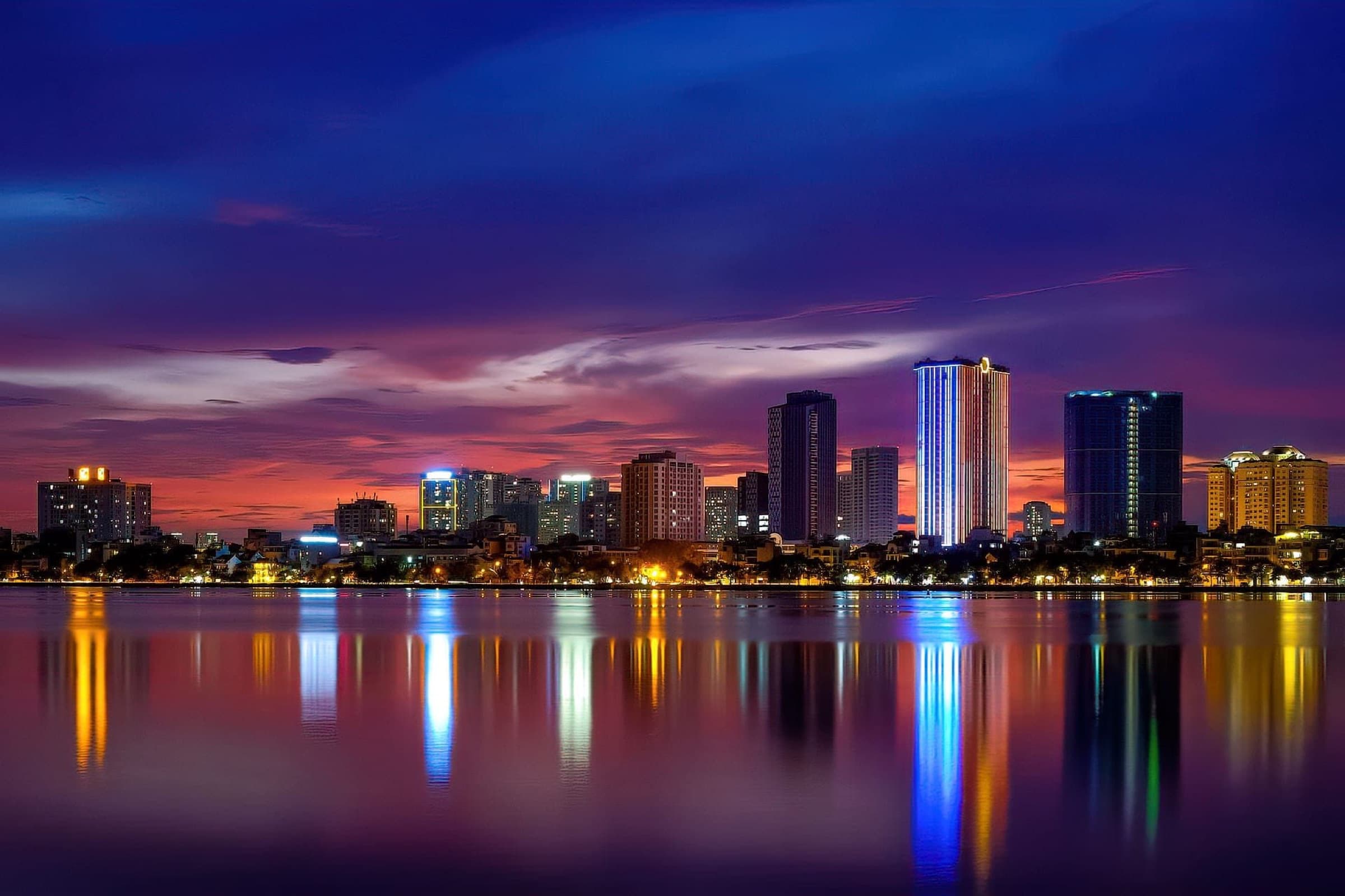 Hanoi's West Lake skyline at dusk, towers reflected in the water