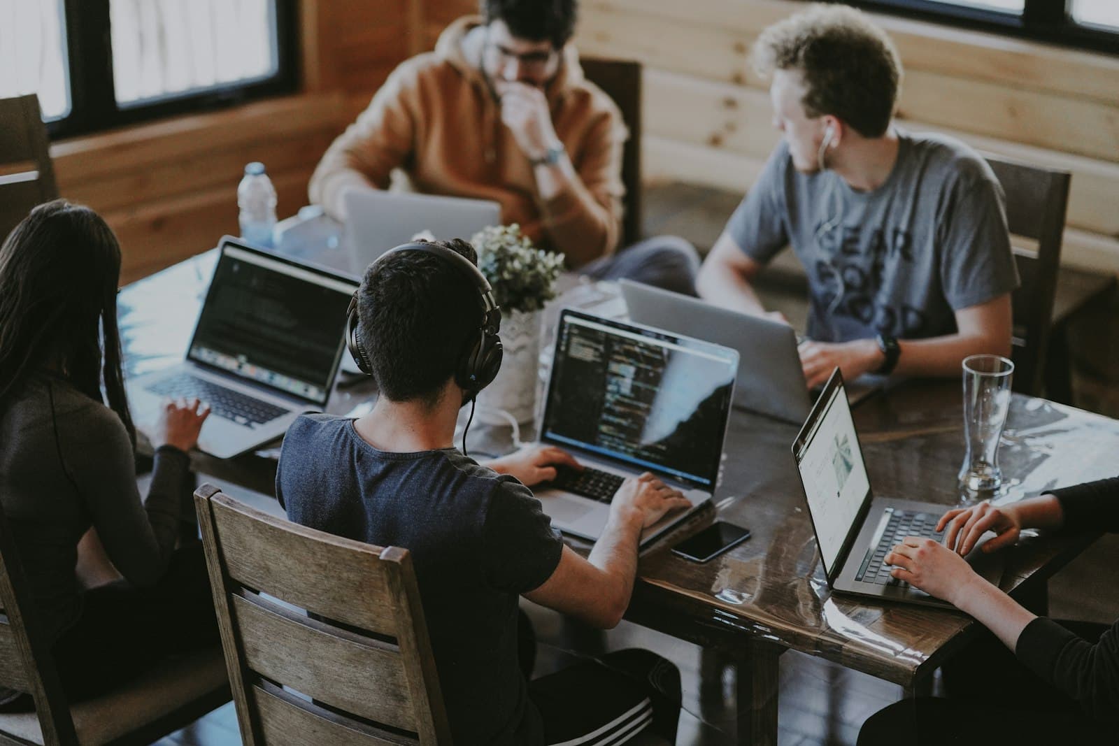 A small team working on laptops around one wooden table