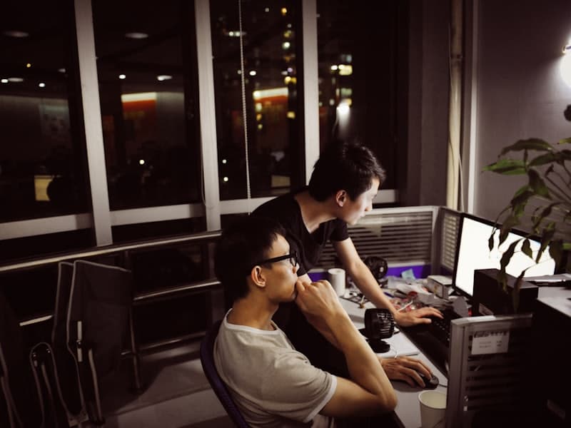 Two people working side by side at their screens late at night