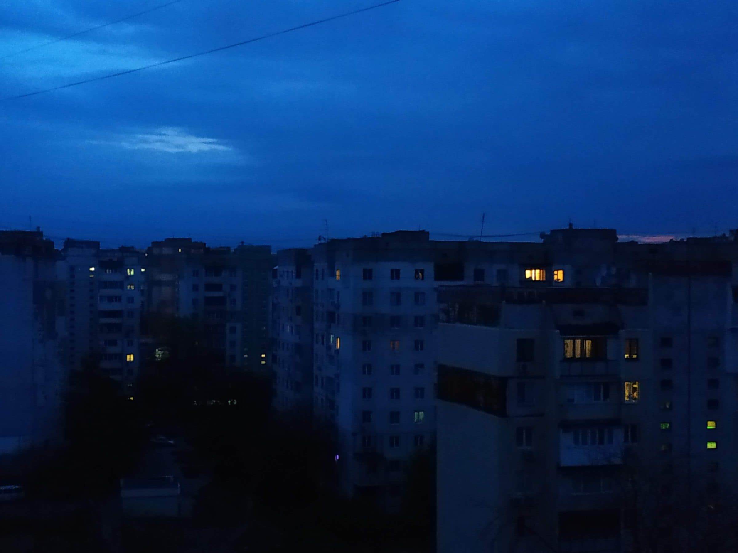 Two glass towers side by side reflecting a city at dusk