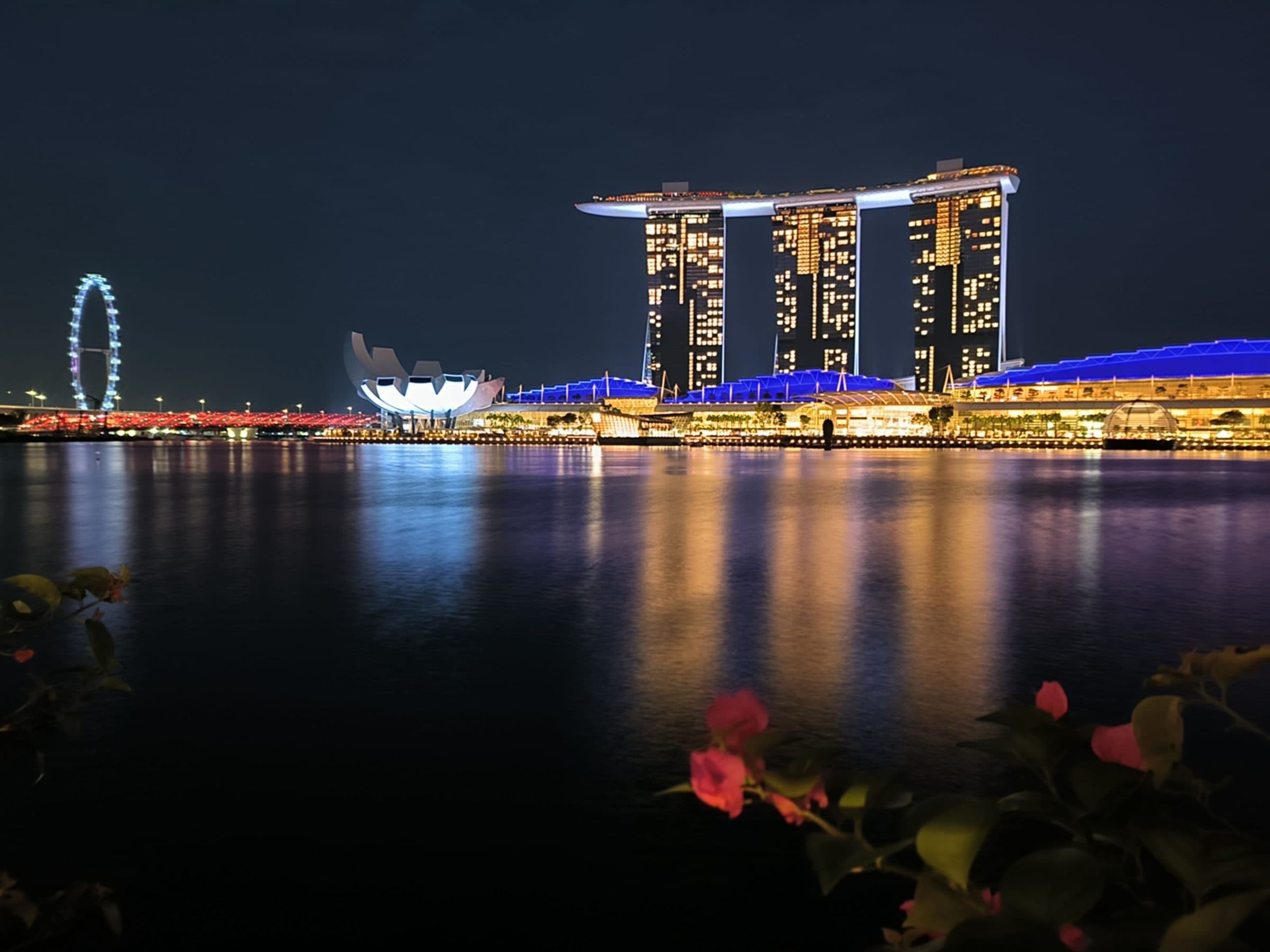 Row of illuminated skyscrapers reflected in still water after dark