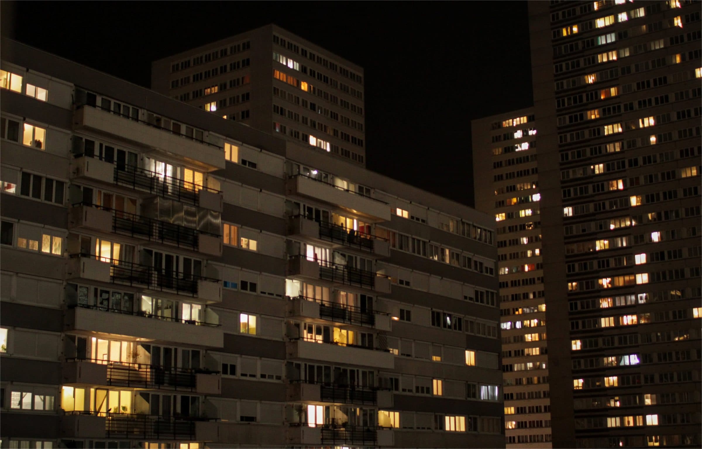 Lit apartment windows across a dark city block at night