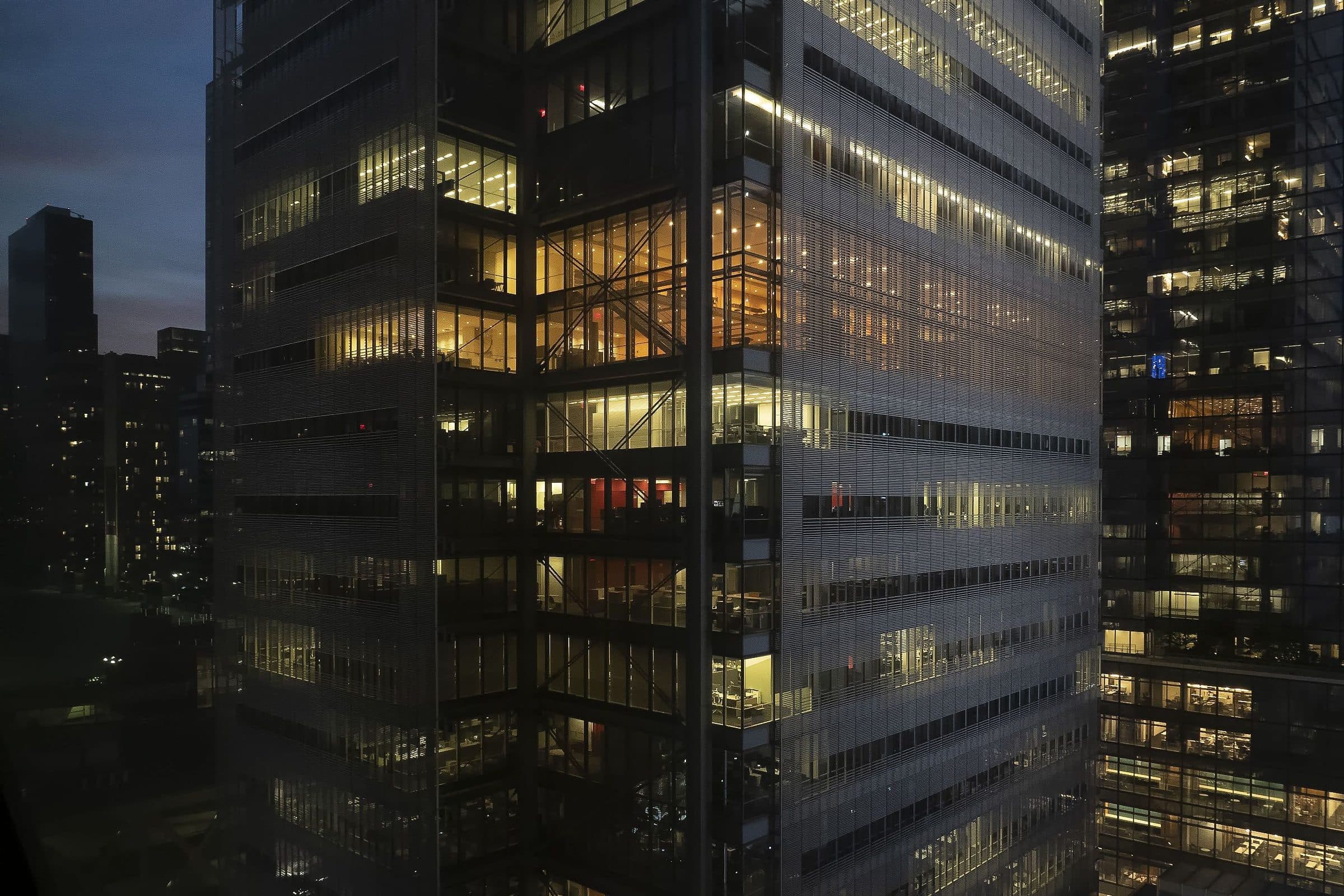 Glass office tower at dusk with a few floors still lit