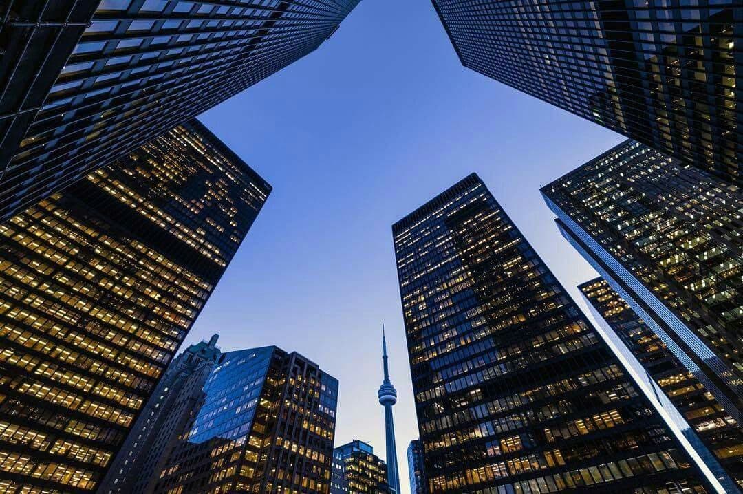 Looking straight up between four glass towers at dusk