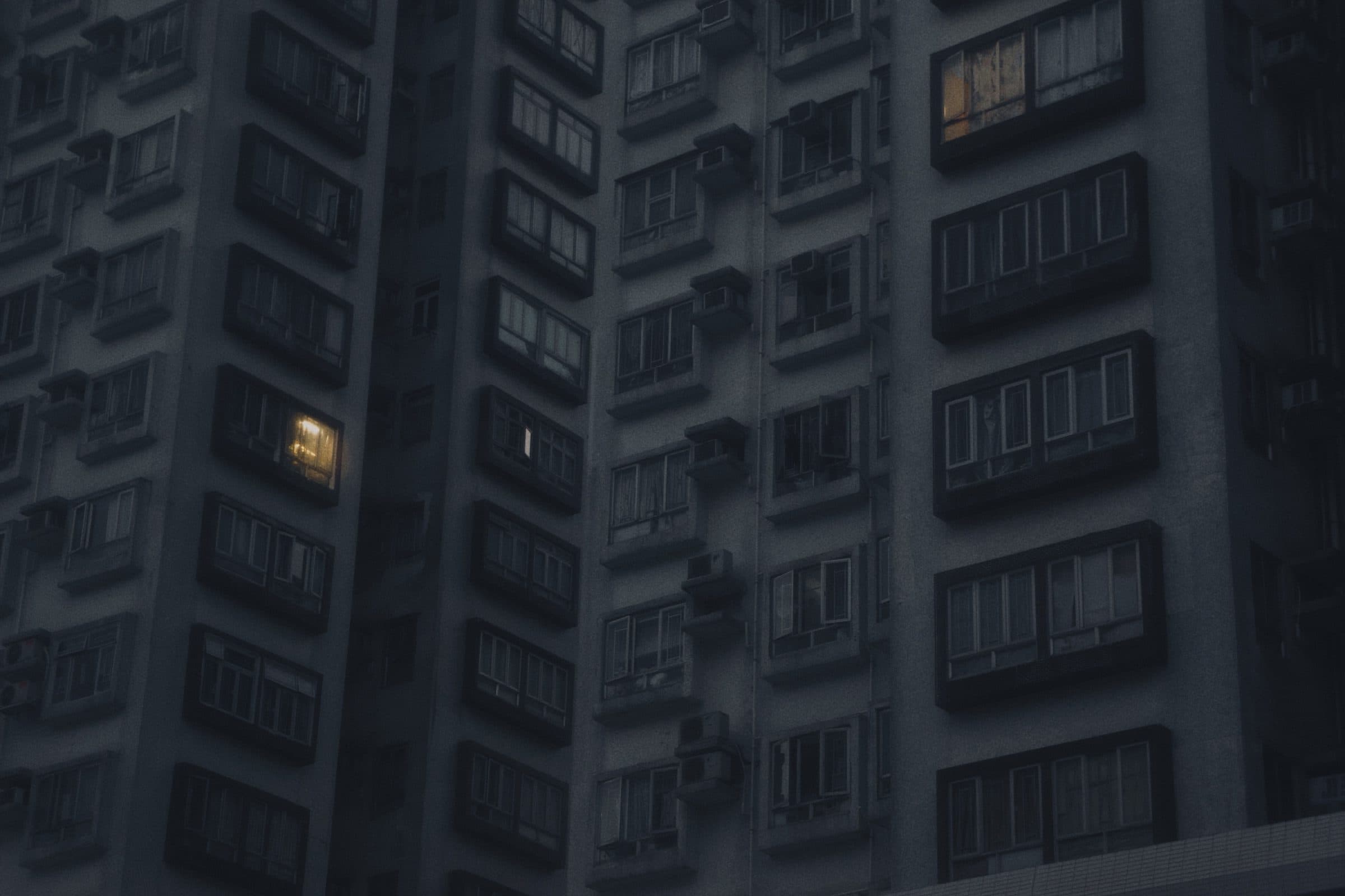 A single lit townhouse on a dark residential street at night