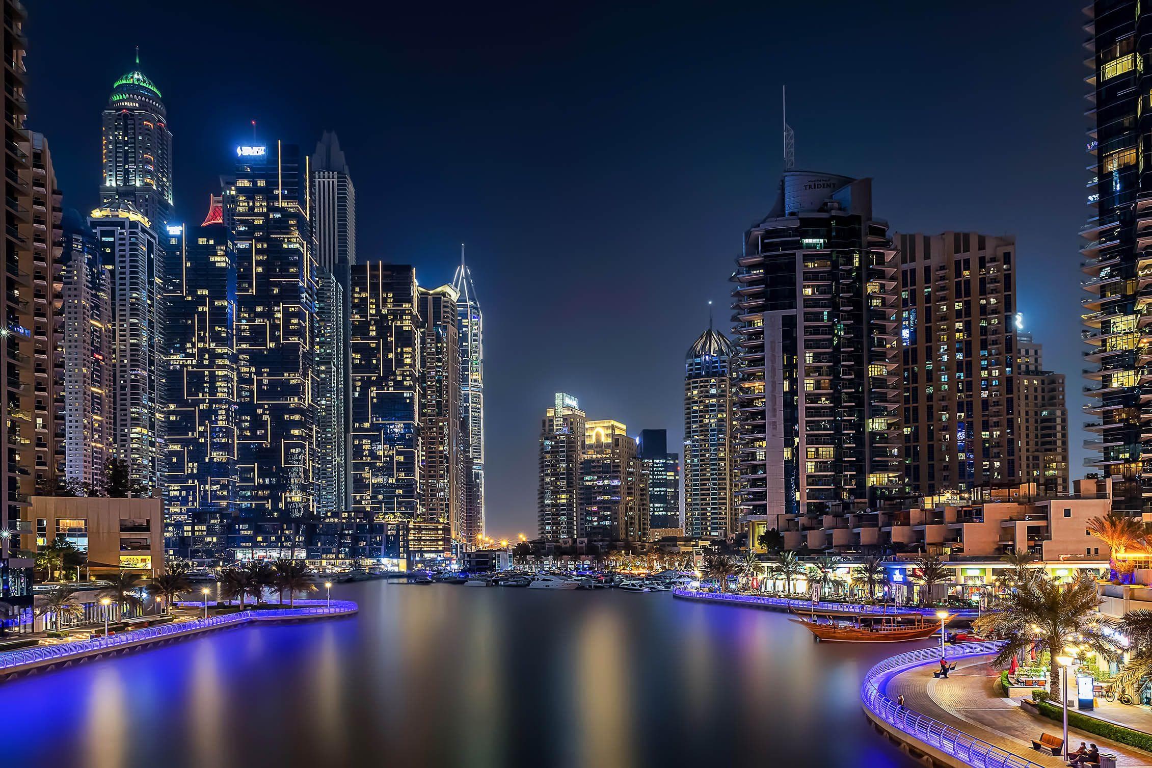 Dubai Marina towers at night with the promenade lights reflected in the water