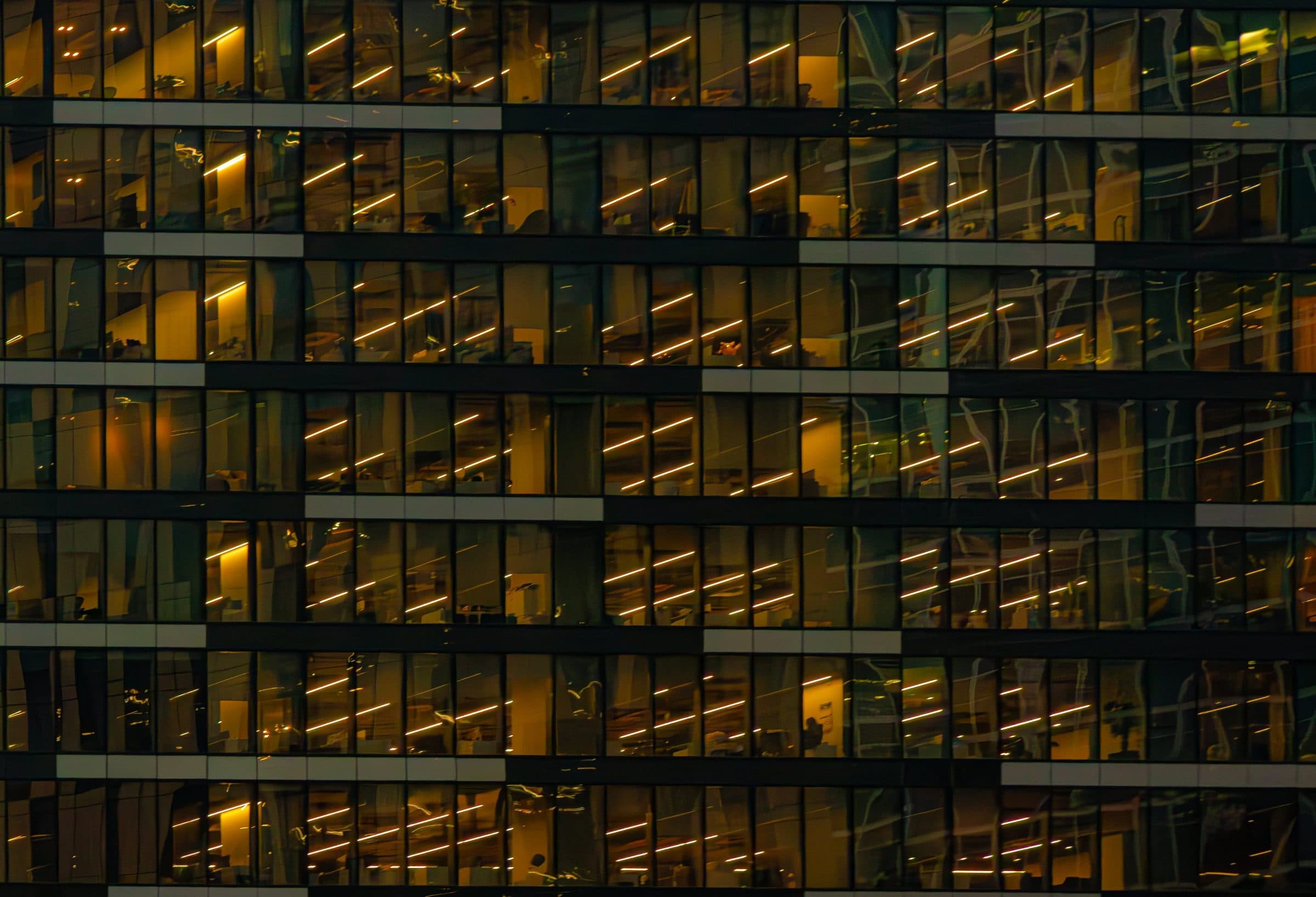 Glass office tower at night with its floors lit in a regular grid